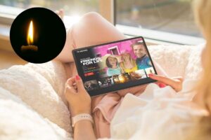 ragazza guarda serie sul tablet a letto e nel cerchietto una candela