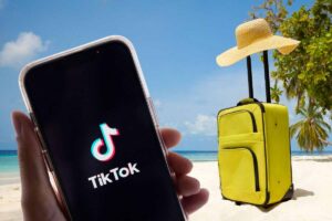 Spiaggia, valigia e smartphone con TikTok