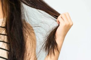 Mano tiene ciocca di capelli crespi