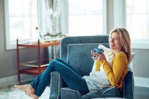 Donna sul divano sorridente con tazza in mano