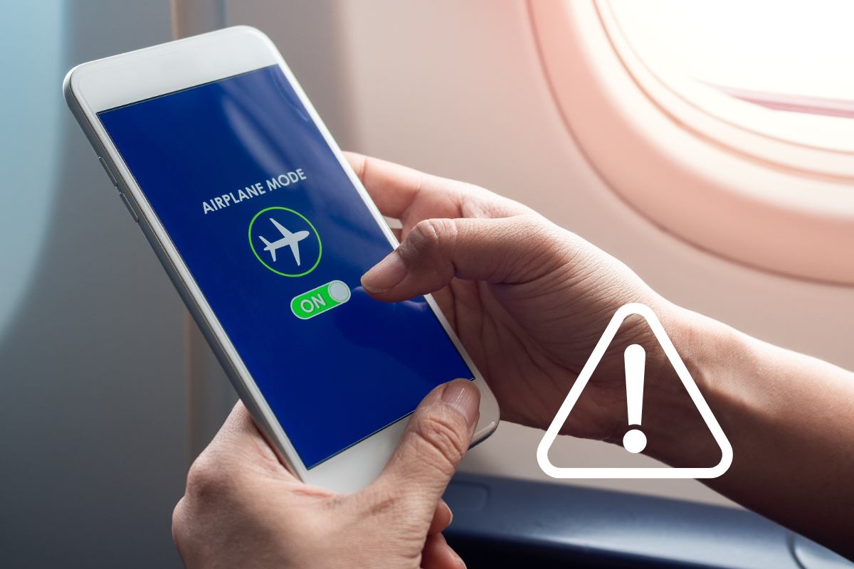 smartphone in mano in aereo e simbolo pericolo